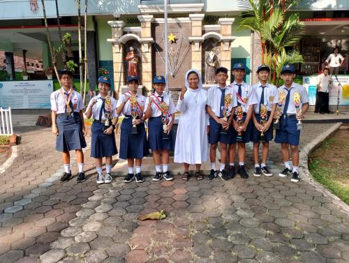Sr. M. Agnesita, OSF, S.Pd., M.Pd selaku kepala sekolah bersama dengan siswa-siswi yang berprestasi, saat selesai upacara bendera sebagai pembiasaan setiap hari Senin.